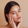 Editorial beauty photo: woman examining her cheek for signs of skin purging vs breakout