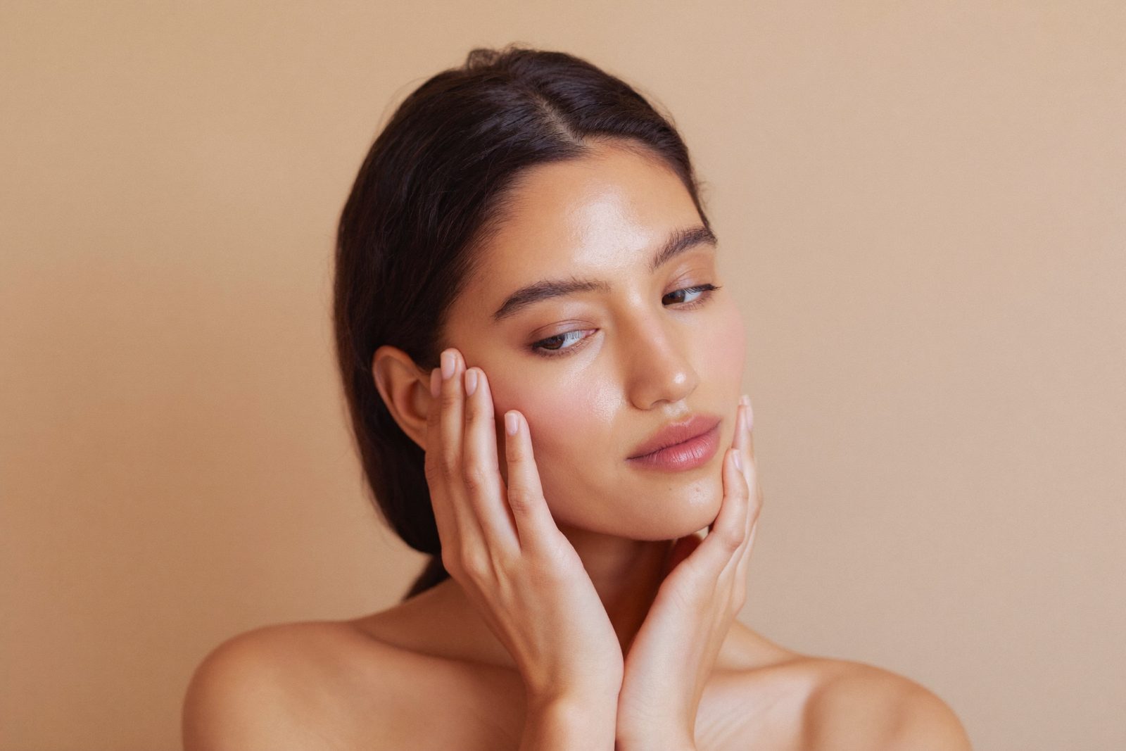Editorial beauty photo: woman examining her cheek for signs of skin purging vs breakout