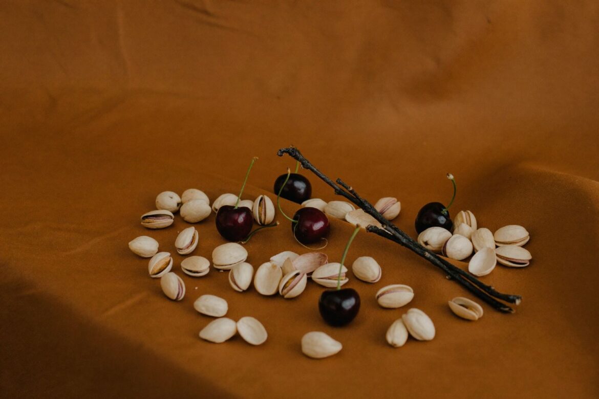 Editorial still life: vanilla pods, cherries and pistachios on caramel silk in golden autumn light