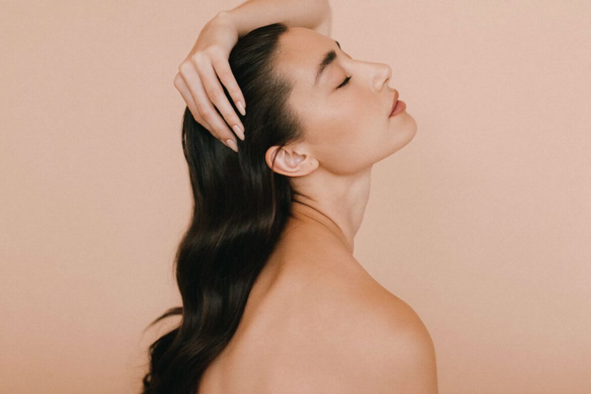 Editorial beauty photo: woman massaging her scalp with fingertips, healthy glossy hair