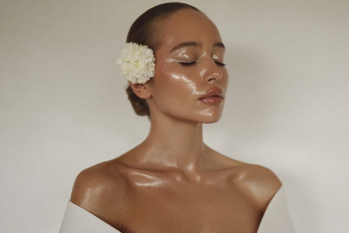 Editorial beauty photo: serene bride with glowing skin and a white flower in her hair